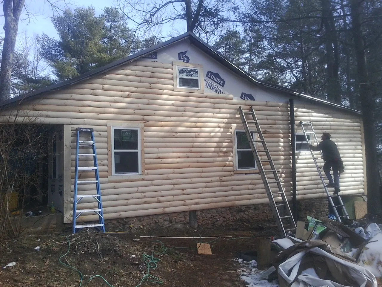 Ladders set against fresh log siding during an exterior remodel in Luling