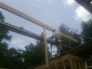 Carpenter setting a ridge beam over a new addition frame — Ice Dam Removal by Roofing Brothers in Luling